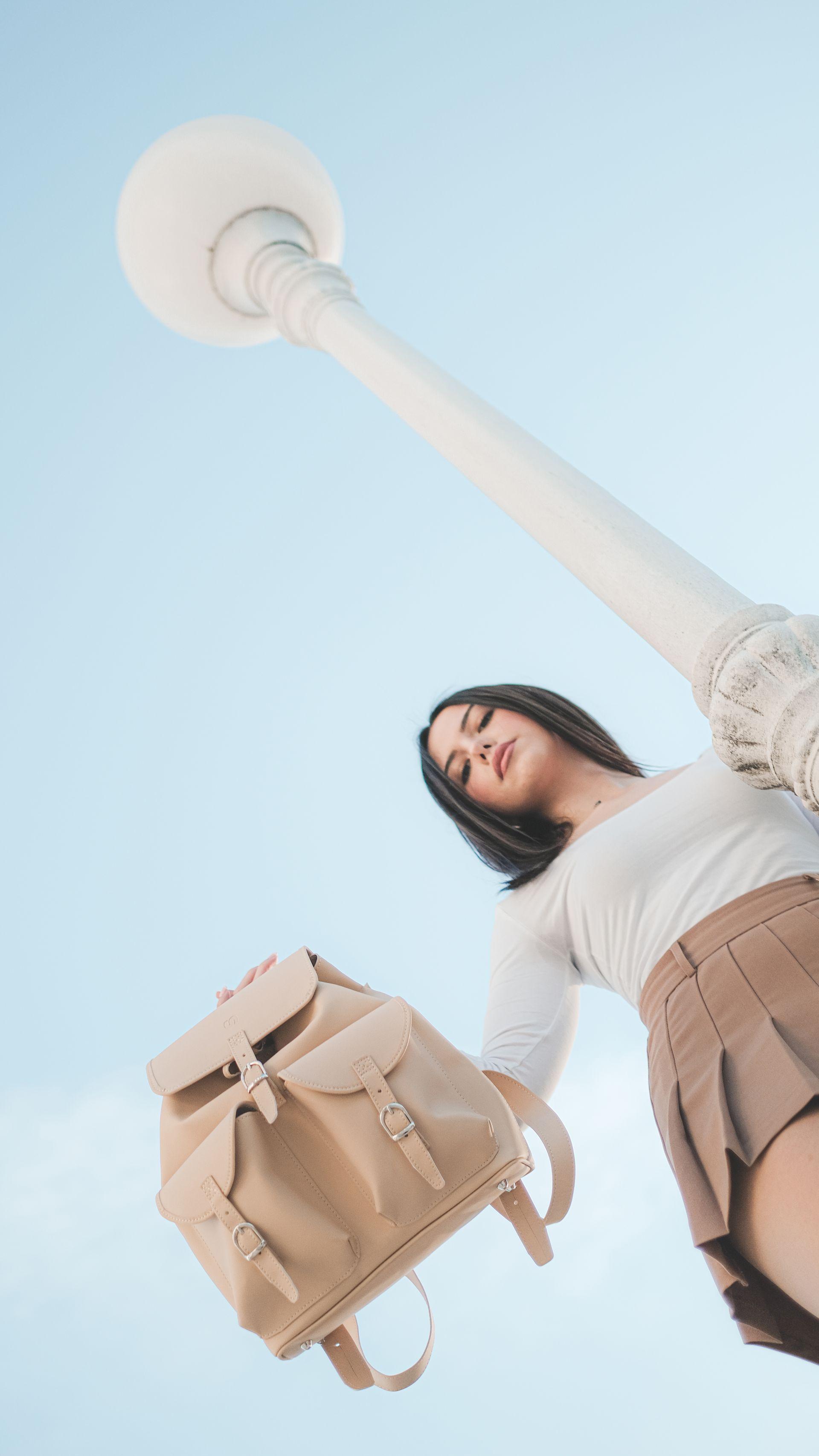 Attractive female model in a skirt holding an tan plant based leather bag