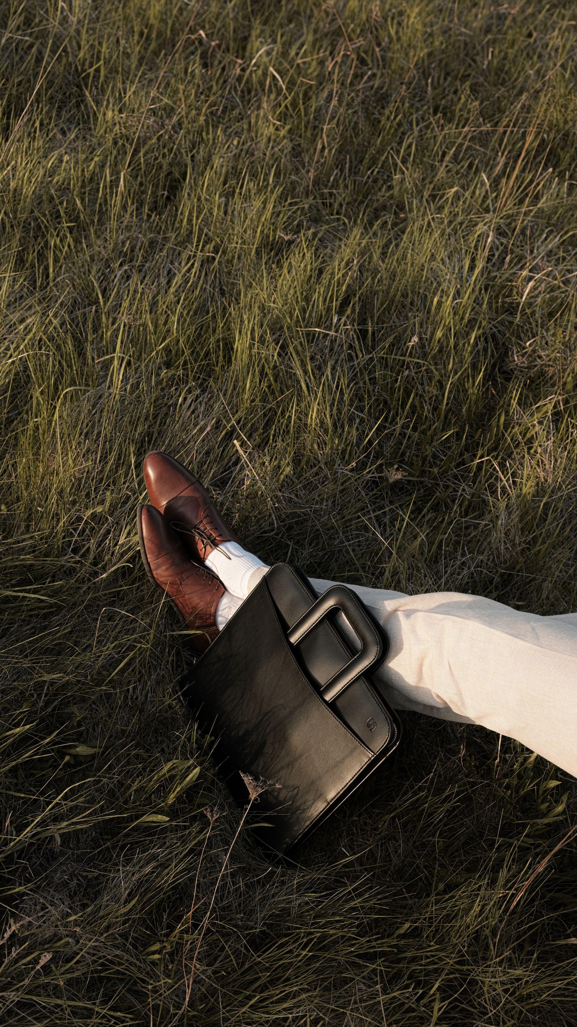 Elegantly dressed man closeup on feet with brown dress shoes and a black leather briefcase