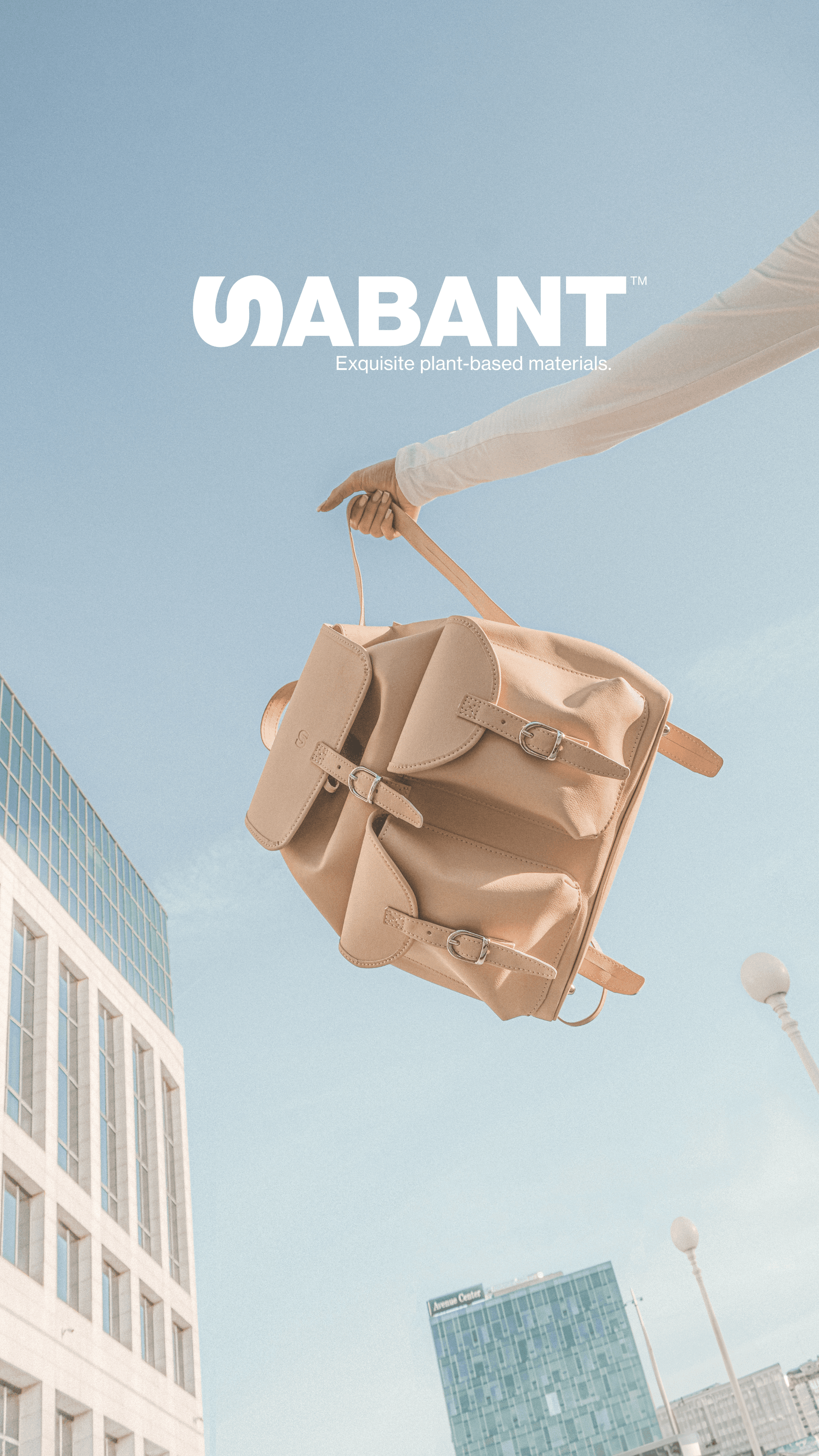 Tan plant based leather bag held in the air with Sabant logo