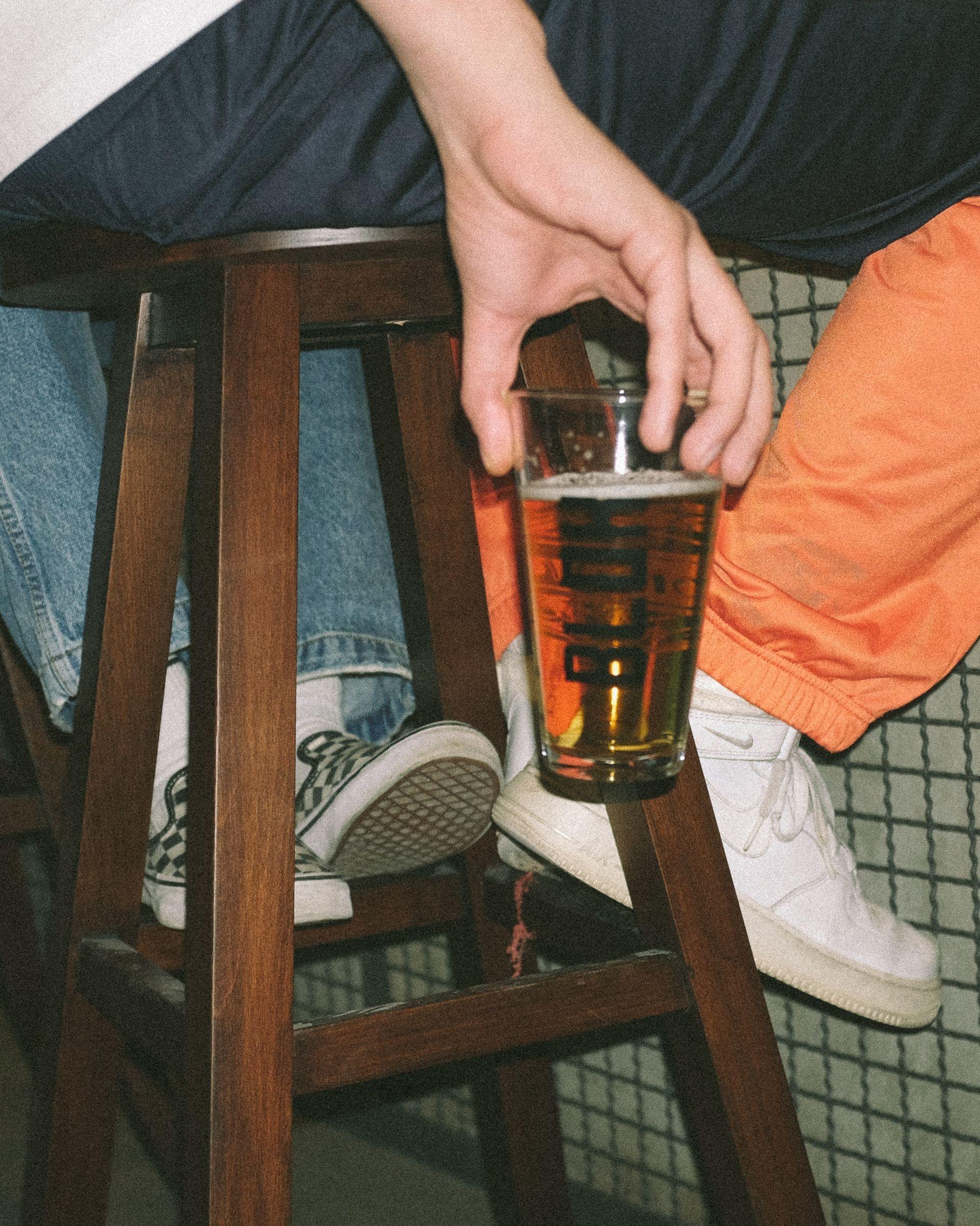 Fashionable man holding a beer glass at the bar closeup on the glass