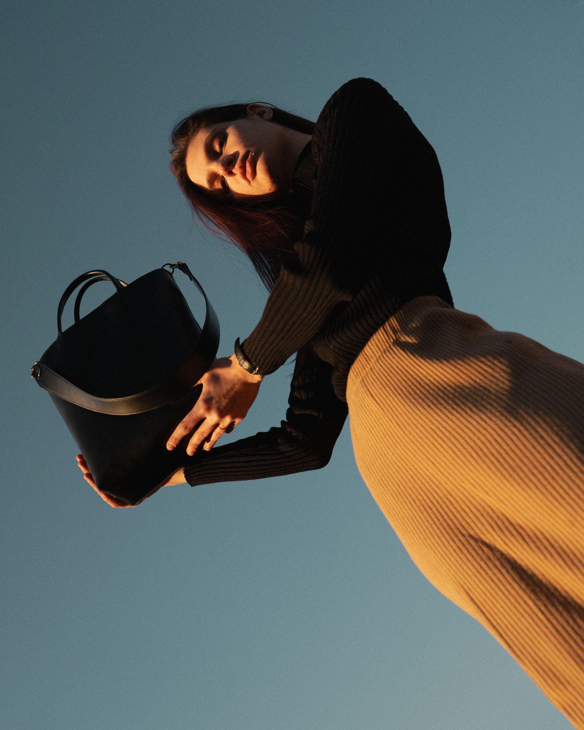 Female good looking model with piercings holding a black leather bag