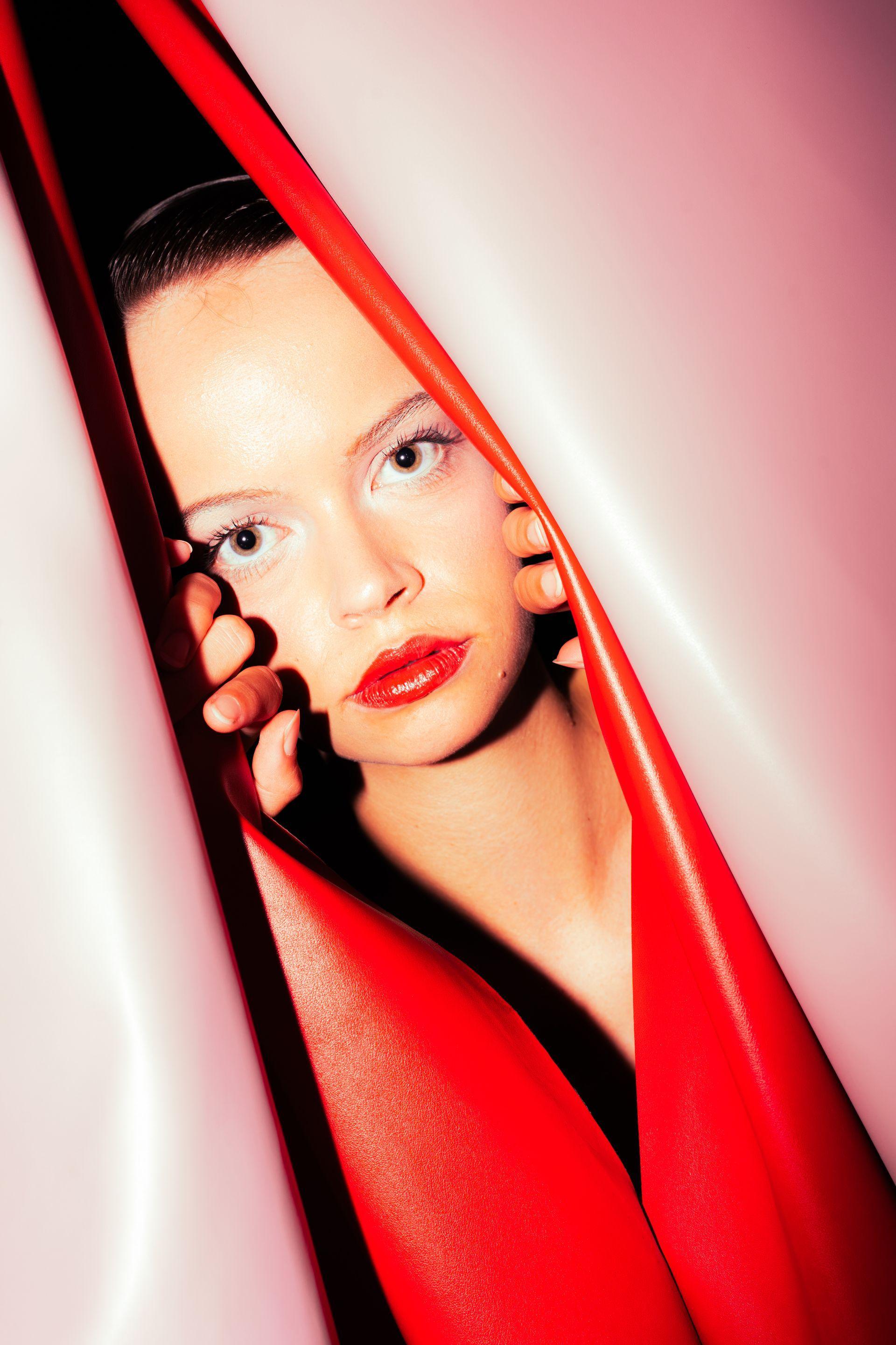 Vintage female model peeking through the red and pink leather curtains